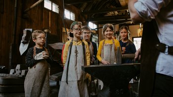 Kinder entdecken die historische Schmiede im Stadtmuseum Steyr.