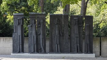 Eine Fotografie des siebenteiligen Figurenreliefs von Fritz Wotruba, die die Skulptur im Skulpturengarten des Belvedere 21 zeigt.