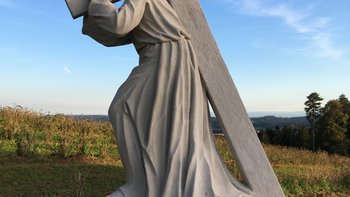 Steinfigur mit Kreuz