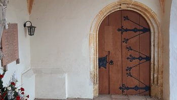 Das Bild zeigt das gotische Südportal mit den in lilienform auslaufenden eisernen Türbändern und geschmiedetem Schloßkasten.