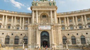 Eingang zur Neuen Hofburg mit dem Altan darüber.. Davor eine große Treppe und zwei Rampen auf der Seite.