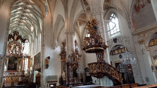 Der Grazer Dom in einer Innenansicht mit Blick auf den Hochaltar und im Zentrum die barocke Kanzel, dahinter zwei der vier Seitenkapellen.