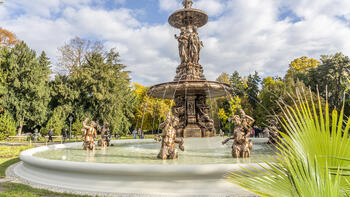 Generalsanierter Grazer Stadtparkbrunnen mit historischem Gusseisenaufbau, Beckenfiguren und Wasserspielen im Stadtpark