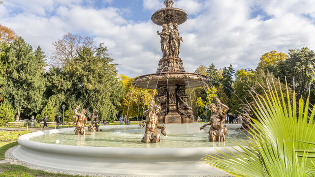 Generalsanierter Grazer Stadtparkbrunnen mit historischem Gusseisenaufbau, Beckenfiguren und Wasserspielen im Stadtpark