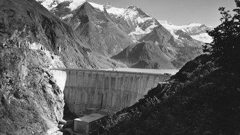 Staumauer und Kraftwerk vor Bergkulisse